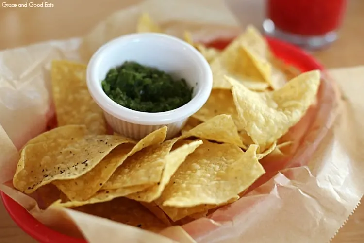 chips and green salsa in a basket lined with parchment paper
