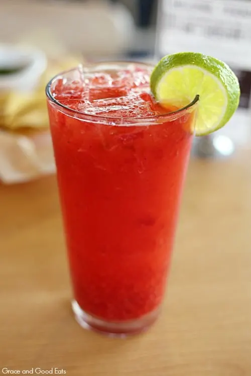 tall glass of red raspberry limeade with a lime wedge