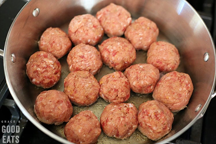 uncooked meatballs in a skillet with oil