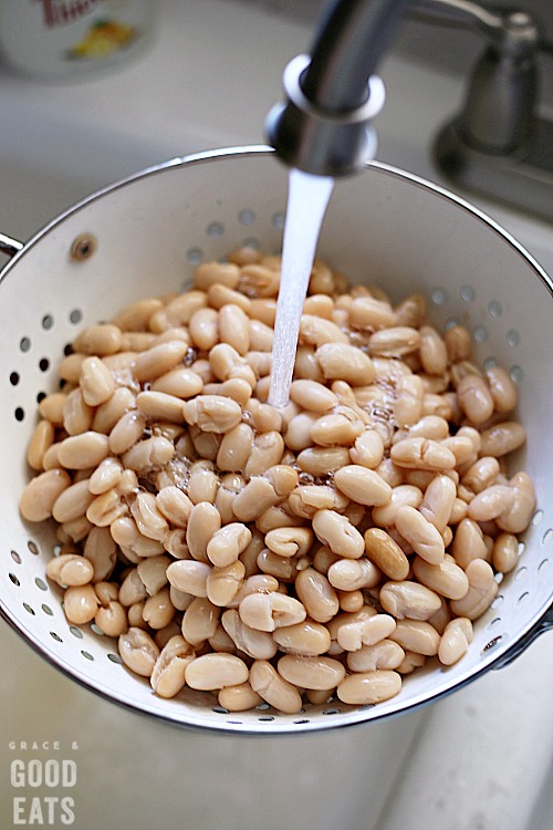 white beans being washed under running water