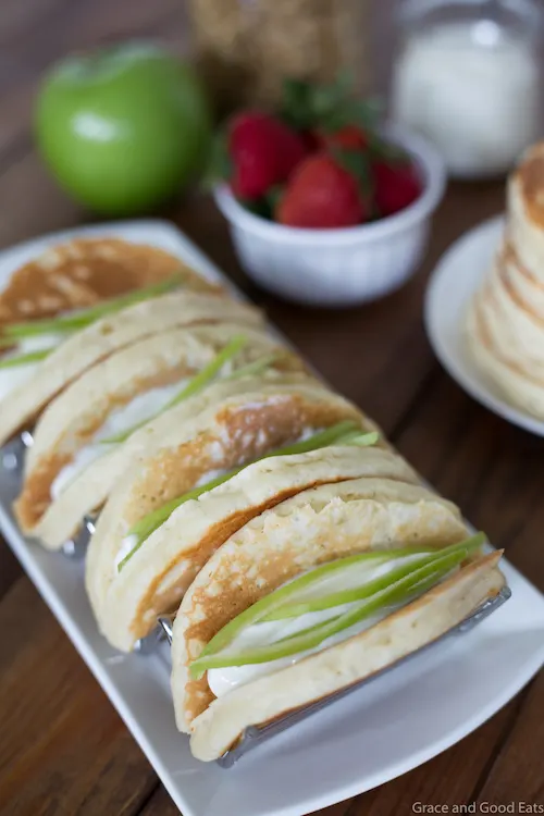 Pancake Parfait Tacos filled with yogurt, granola, apples, and strawberries and topped with a drizzle of honey.  Serve with breakfast potatoes or scrambled eggs for an easy, kid-friendly breakfast!