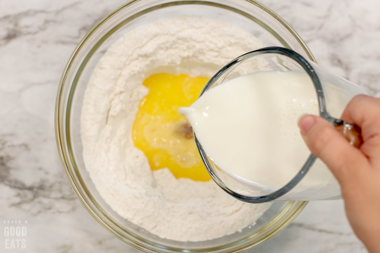 pouring milk into a bowl of pancake ingredients