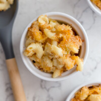 tre piccoli stampini di maccheroni e formaggio, accanto a un grande cucchiaio