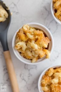 three small ramekins of macaroni and cheese next to a large spoon