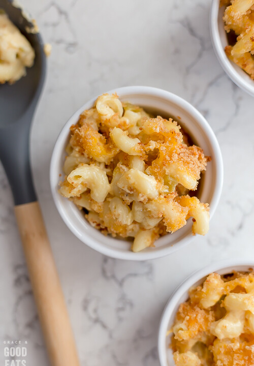 three small ramekins of macaroni and cheese next to a large spoon