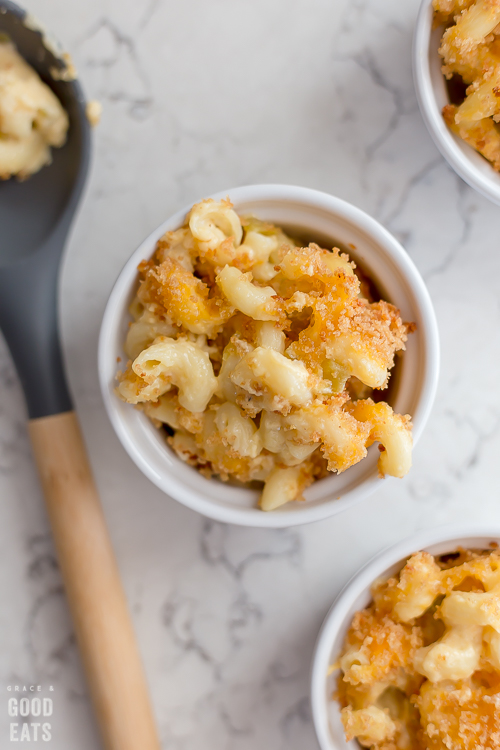  tres ramekins pequeños de macarrones con queso junto a una cuchara grande