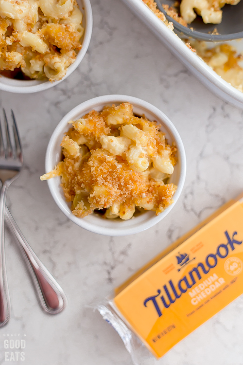 Small ramekin of macaroni and cheese next to a block of cheddar