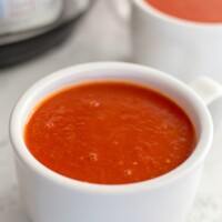 two bowls of tomato soup next to an Instant Pot pressure cooker