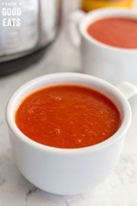two bowls of tomato soup next to an Instant Pot pressure cooker