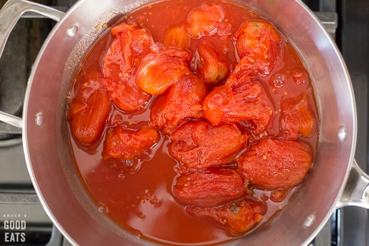 sauce pan full of whole peeled tomatoes with juice