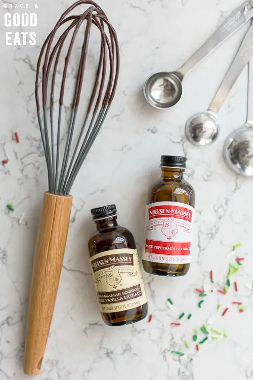 a whisk next to a bottle of Nielsen-Massey vanilla and peppermint extract