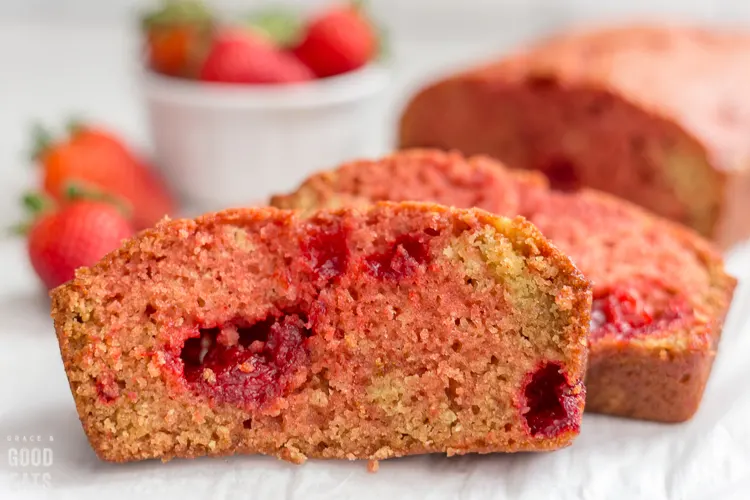 baked strawberry quick bread next to a bowl of strawberries