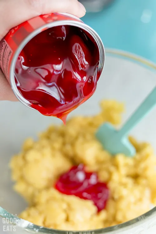 pouring strawberry pie filling into a mixing bowl