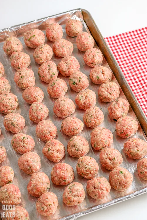 uncooked meatballs shaped into balls on a baking sheet