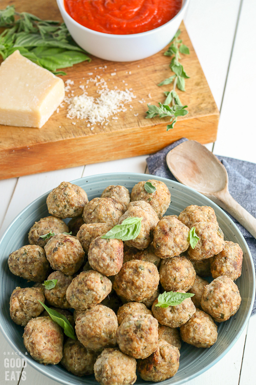 plated meatballs with Parmesan and tomato sauce in the background