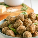 meatballs stacked on a plate topped with basil