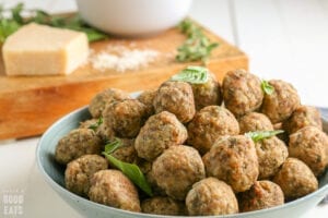 meatballs stacked on a plate topped with basil