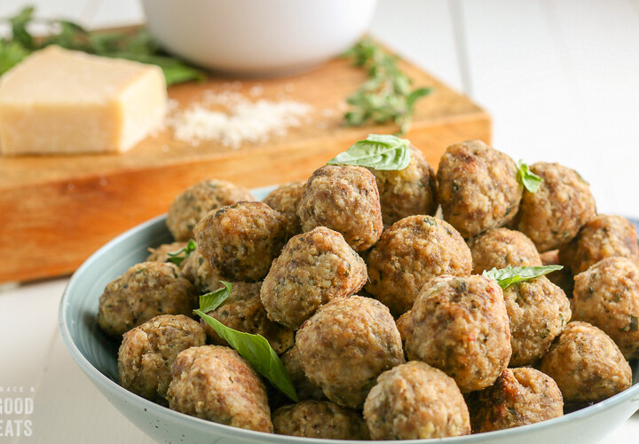 meatballs stacked on a plate topped with basil