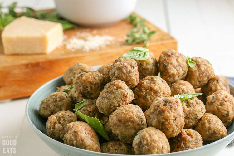 meatballs stacked on a plate topped with basil