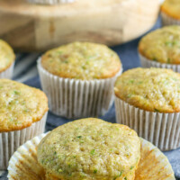 closeup of a zucchini muffin without the liner next to more muffins