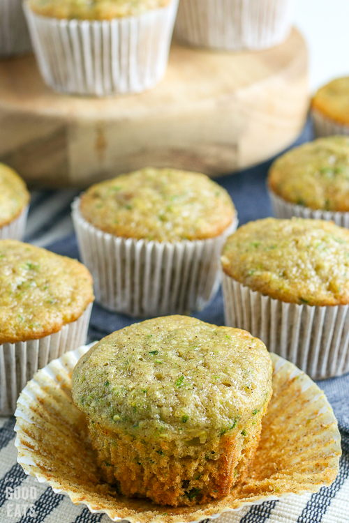 closeup of a zucchini muffin without the liner next to more muffins