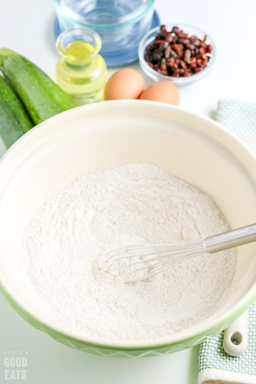 large mixing bowl of flour with a silver whisk