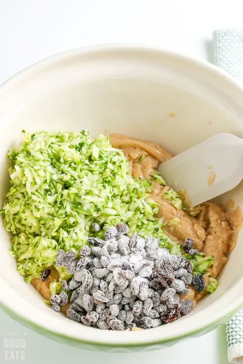 mixing bowl with muffin batter, grated zucchini, and raisins