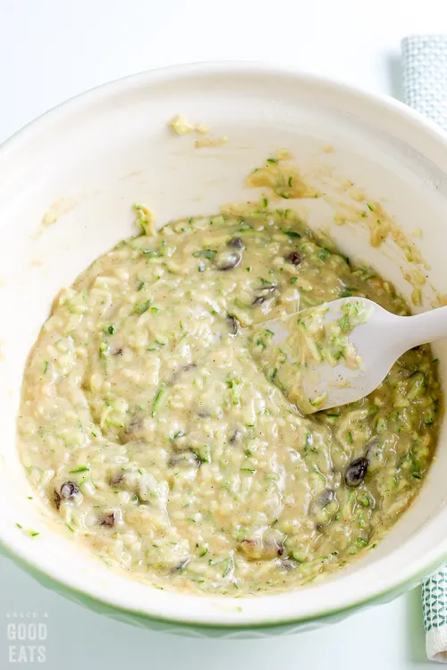 mixing bowl with pale green zucchini muffin batter all combined