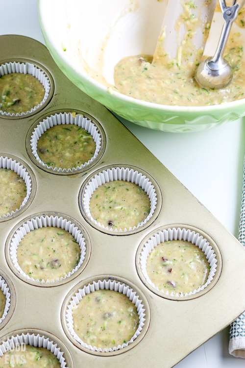 zucchini muffin batter in a muffin tin with white paper liners