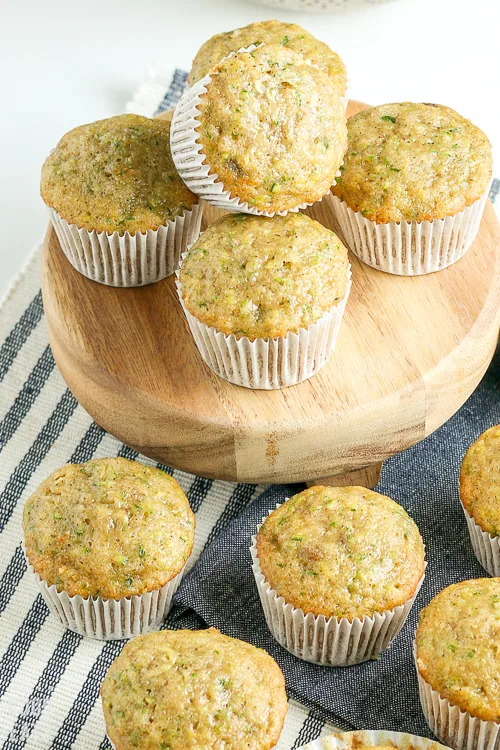 zucchini muffins stacked on a small round cutting board