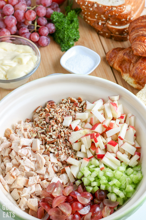chopped chicken, apples, celery, pecans, and grapes in a white bowl