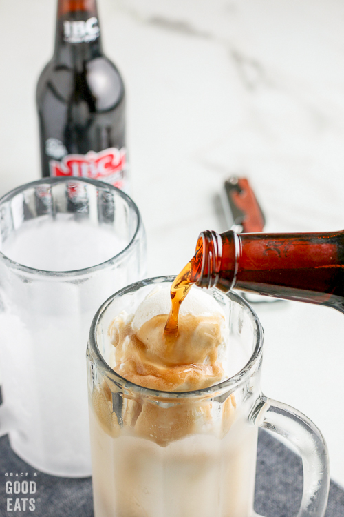 pouring root beer into a mug