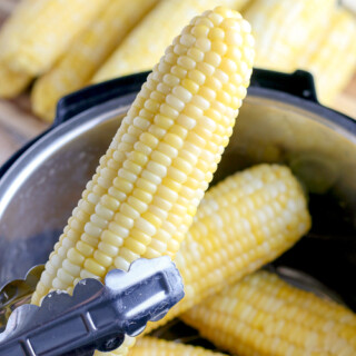 holding an ear of corn with metal tongs
