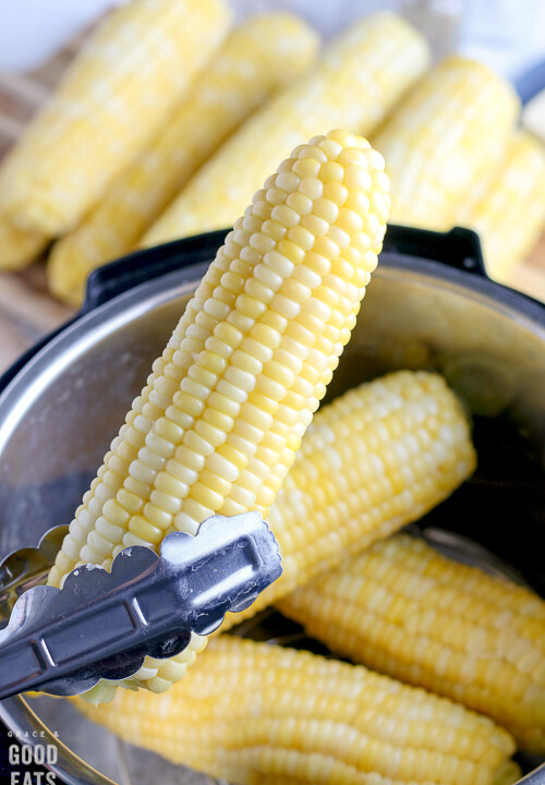 holding an ear of corn with metal tongs