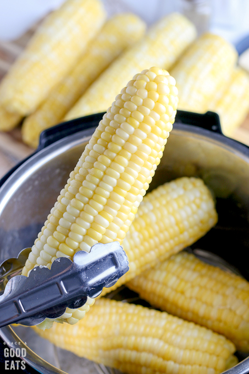 holding an ear of corn with metal tongs