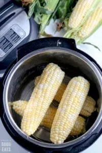 four uncooked ears of corn in a pressure cooker