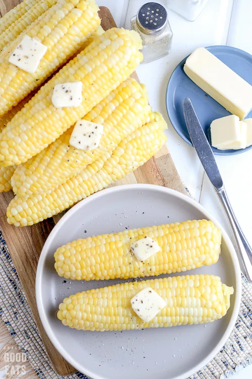 two ears of corn with butter on a plate
