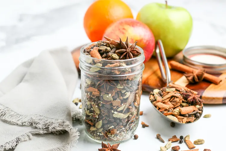 mulling spices with apples and an orange in the background