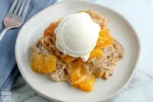 closeup of white plate with peach cobbler and vanilla ice cream