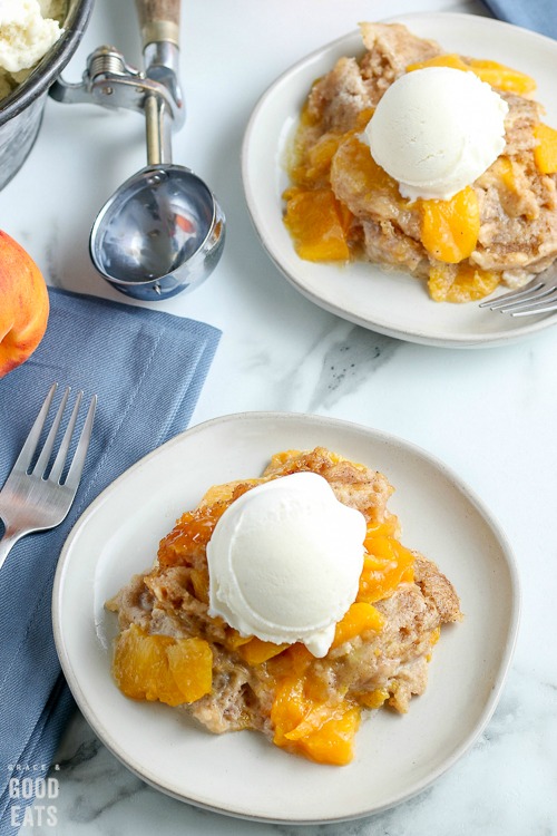 overhead shot of two plates with peach cobbler and vanilla ice cream