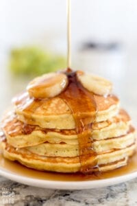 pancakes topped with syrup and bananas on a white plate