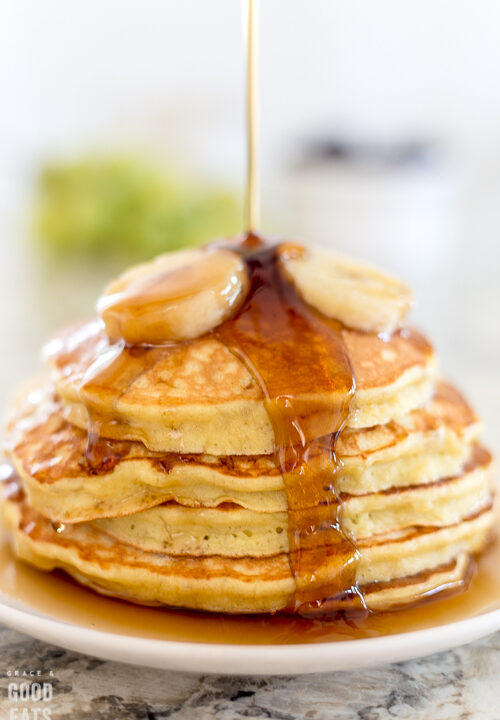 pancakes topped with syrup and bananas on a white plate