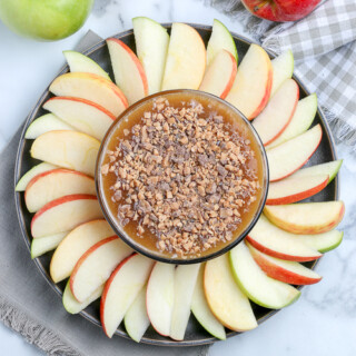 overhead view of a bowl of caramel apple dip with apples around it