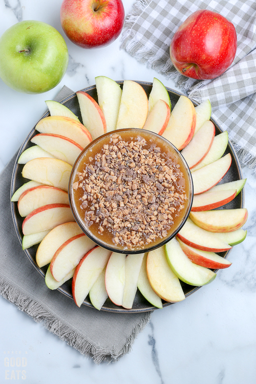 overhead view of a bowl of caramel apple dip with apples around it