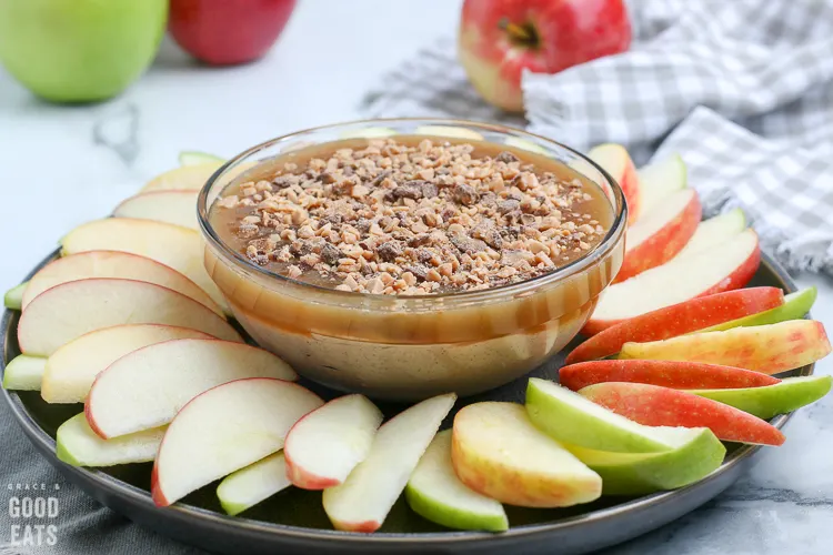 caramel apple dip surrounded by apple slices on a platter