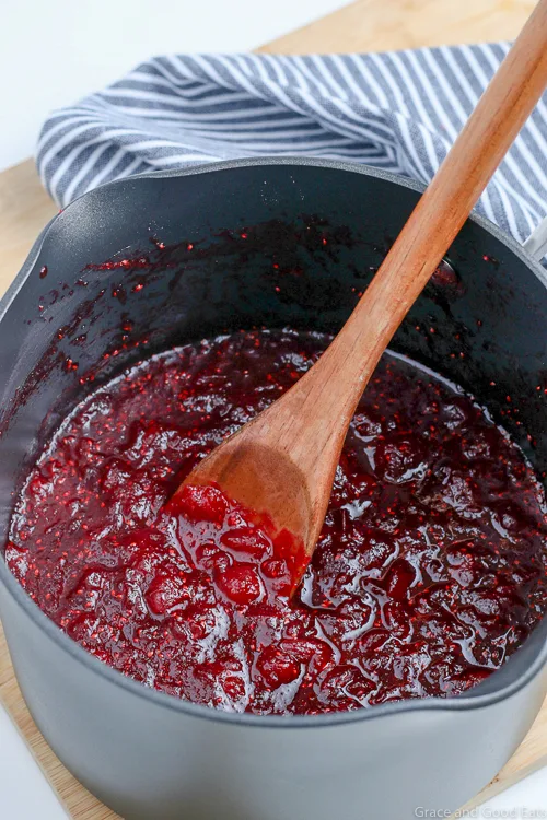 cooked cranberries in a saucepan with wooden spoon