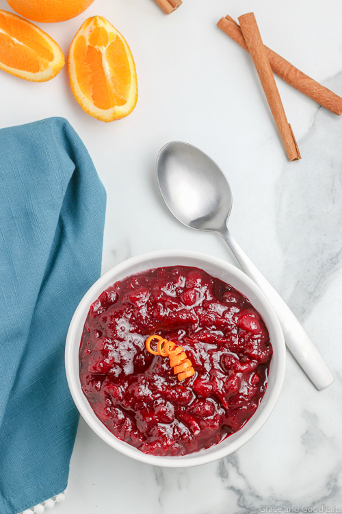 bowl of cranberry sauce next to a spoon and blue napkin