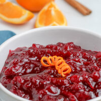 bowl of fresh cranberry sauce in a bowl with orange in the background