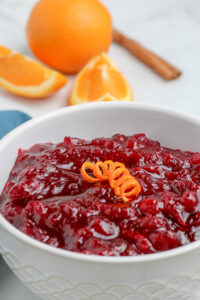 bowl of fresh cranberry sauce in a bowl with orange in the background