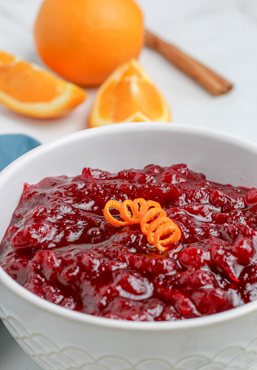 bowl of fresh cranberry sauce in a bowl with orange in the background